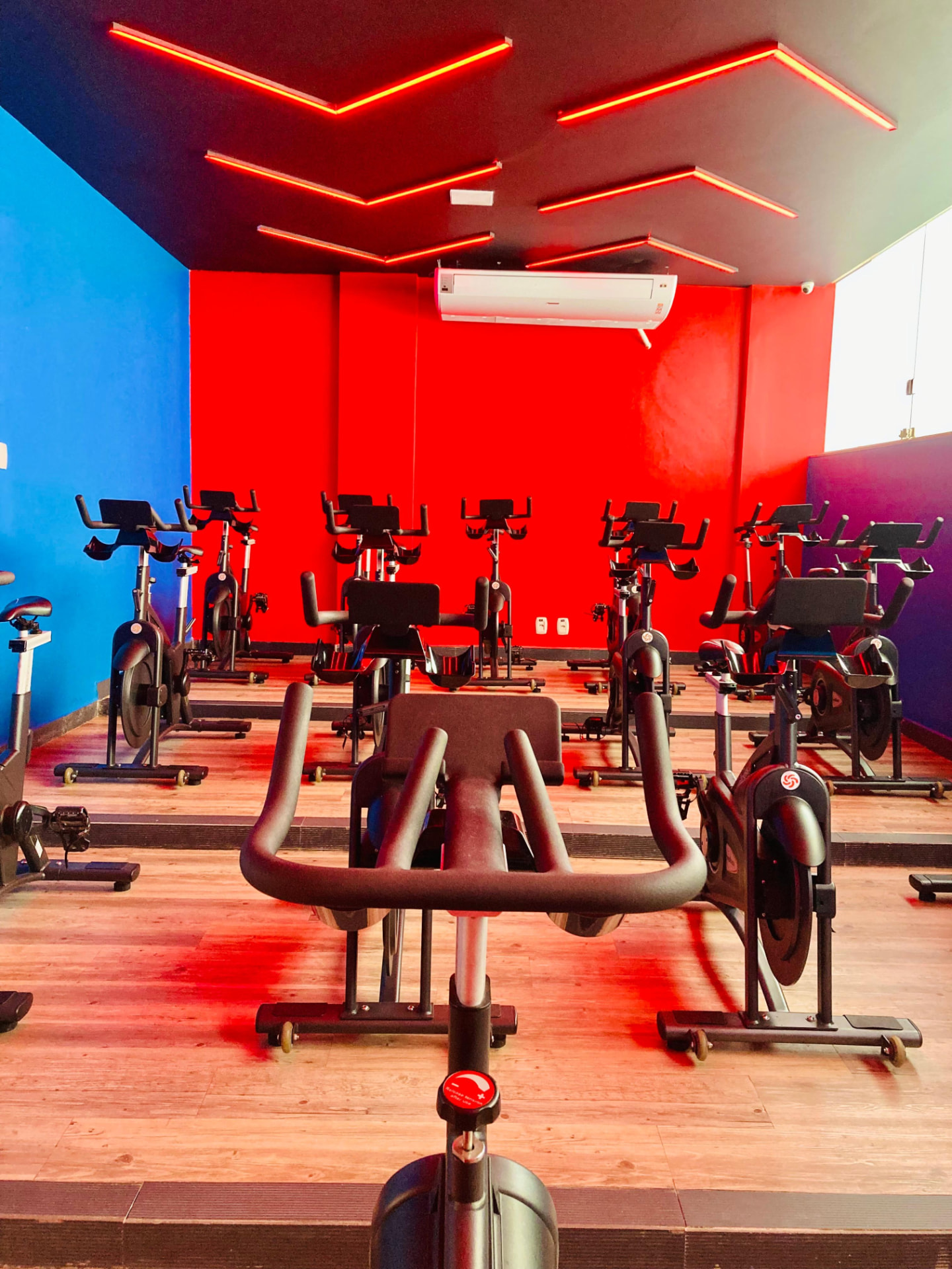 Sala de spinning vermelha e azul da Rayafit Itapuã